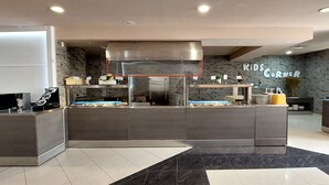 A modern kitchen area with a central island, stainless steel appliances, and a wall with the text 'Kids Corner'. - Aquamarine Hotel (Nessebar)