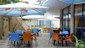 A terrace with outdoor seating, covered by umbrellas, and a staircase leading to an upper level. - Aquamarine Hotel (Nessebar)