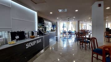 A restaurant with a soup bar, dining tables, chairs, and a tiled floor.