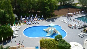 A swimming pool with a water slide, lounge chairs, and umbrellas. - Aquamarine Hotel (Nessebar)