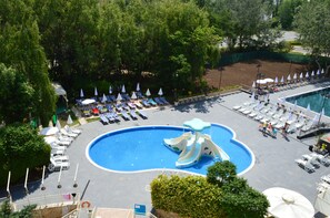 A swimming pool with a water slide, lounge chairs, and umbrellas. - Aquamarine Hotel (Nessebar)