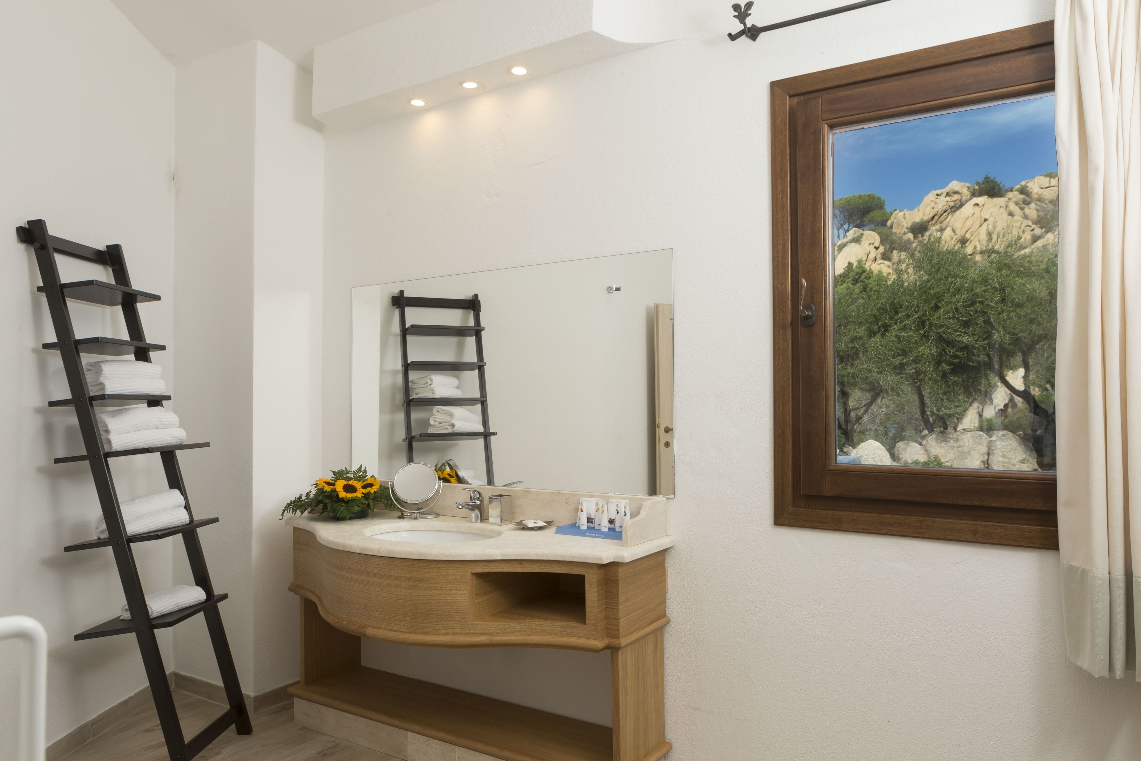 Un ba ño con tocador de madera, un espejo, un lavamanos y un perchero para toallas.