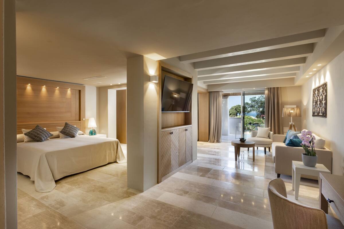Una habitación de hotel moderna con cama, televisor, sofá y mesa de centro.