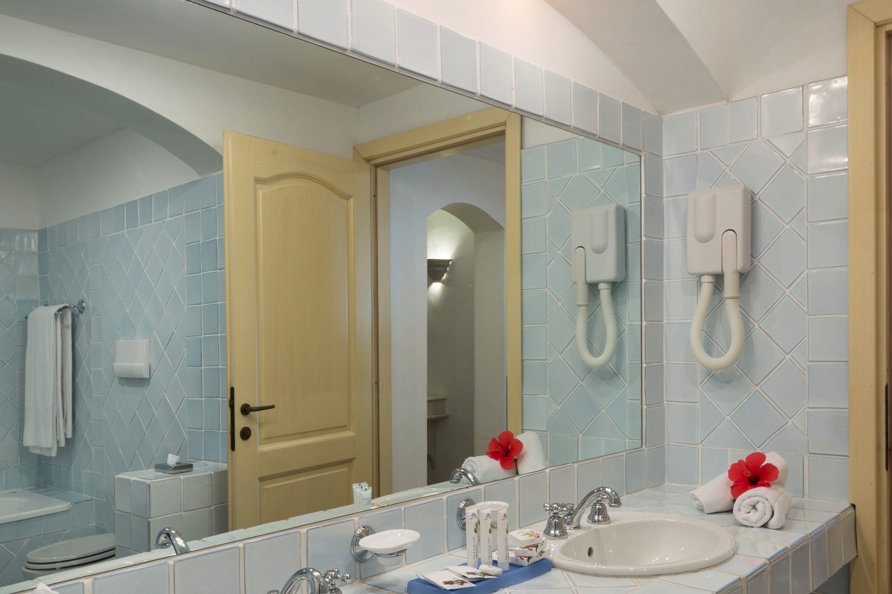 A bathroom with a large mirror, a sink, a toilet, and a shower area.