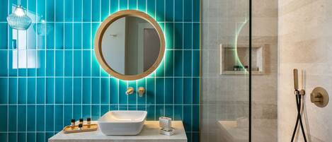 Un baño moderno con un espejo grande, un lavabo blanco y una ducha con mampara de vidrio.