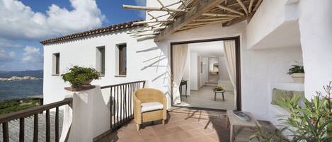 A balcony with a wicker chair, a small table, and potted plants.