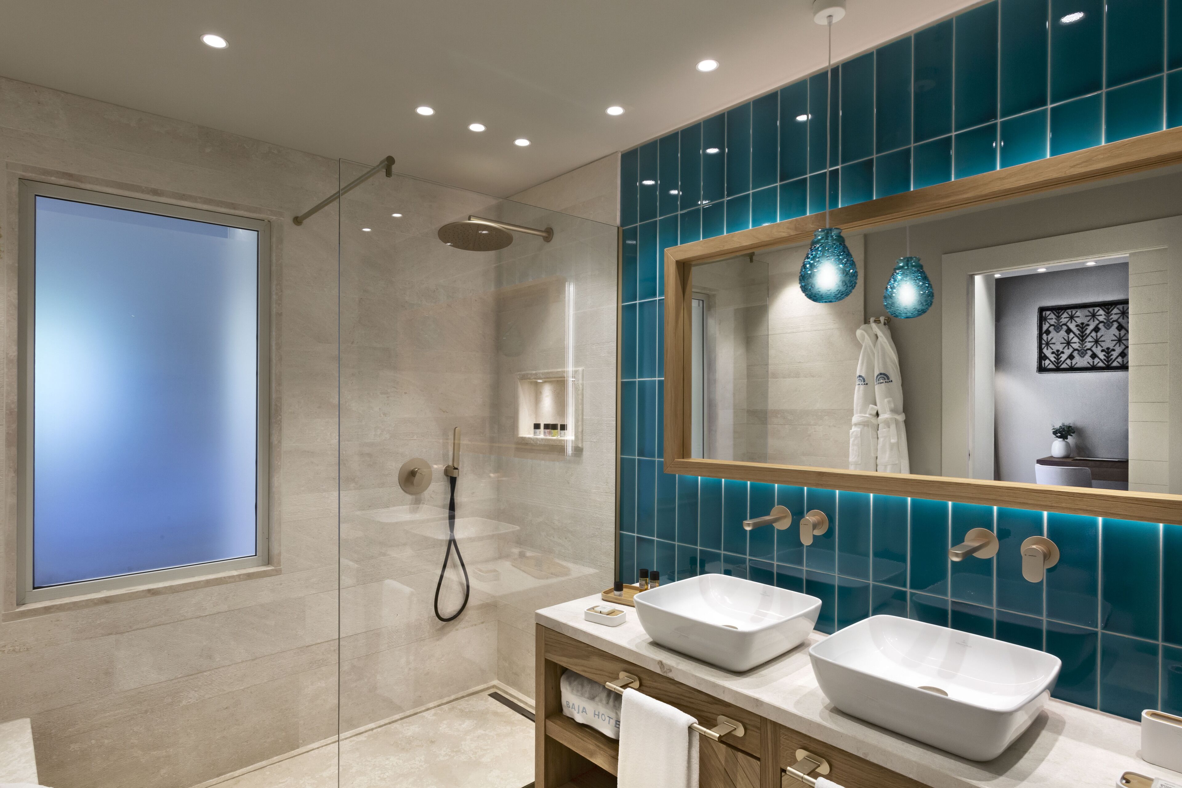 A modern bathroom with a large mirror, two sinks, and a shower.