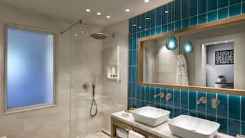 A modern bathroom with a large mirror, two sinks, and a shower.
