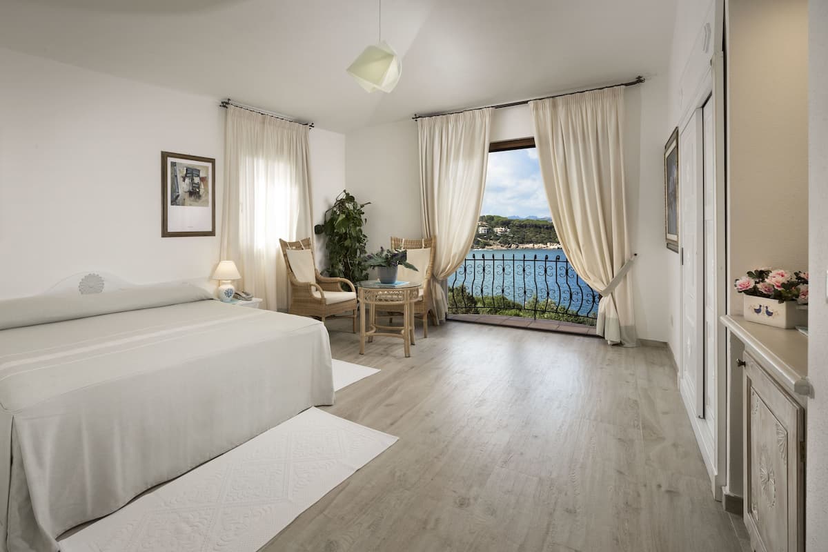 Habitación de hotel con cama, una silla, una mesa y vistas al mar.