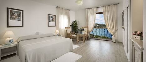 Habitación de hotel con cama, una silla, una mesa y vistas al mar.