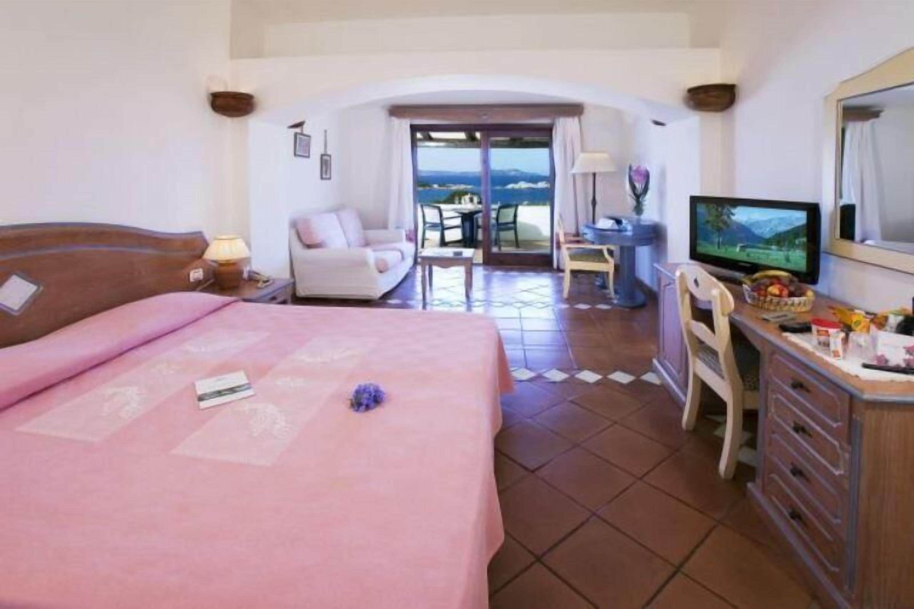 Une chambre d’hôtel avec un lit, un bureau avec une télévision, une chaise et une vue sur l’extérieur.