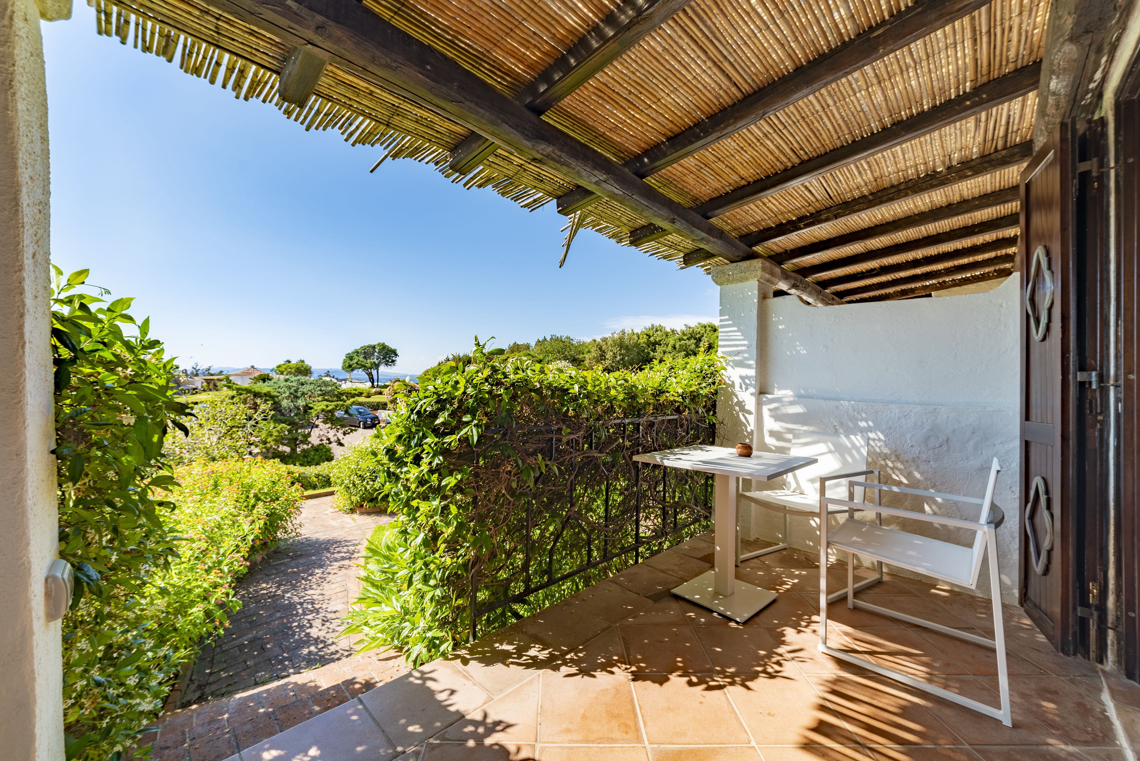 Un espace extérieur abrité, doté d’une table et de chaises, entouré de verdure et offrant une vue dégagée sur le paysage.