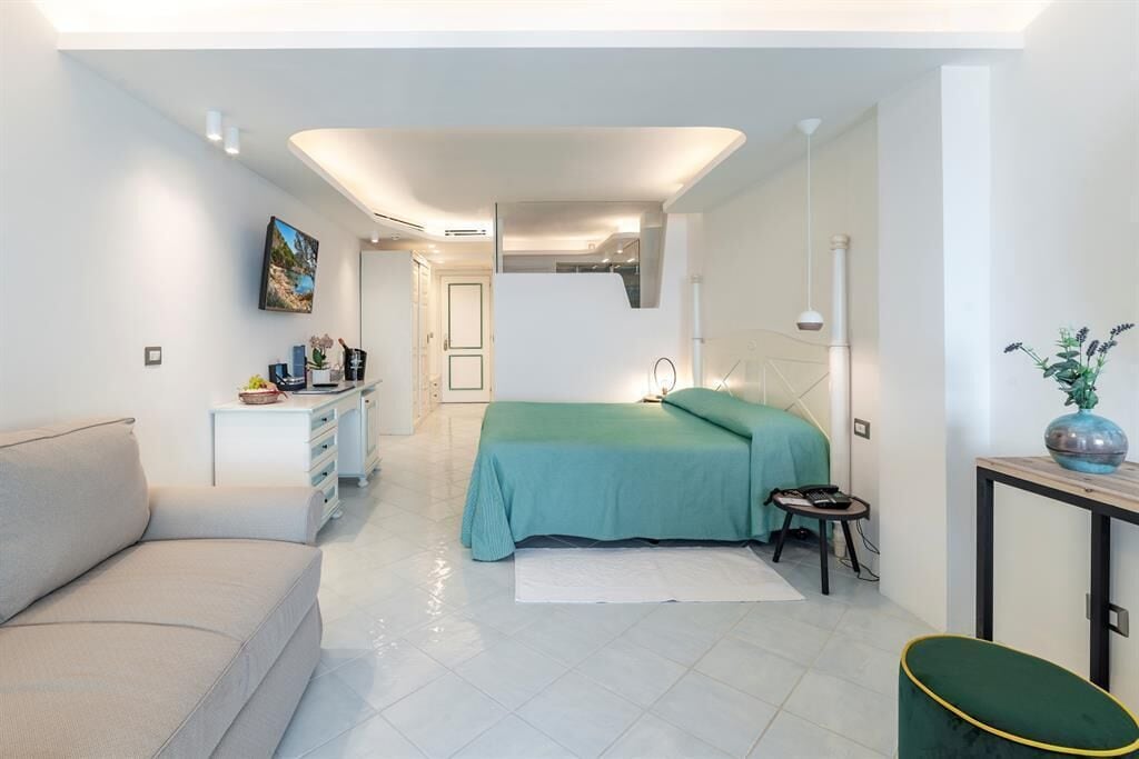 A modern bedroom with a bed, a sofa, a small table, and a desk.