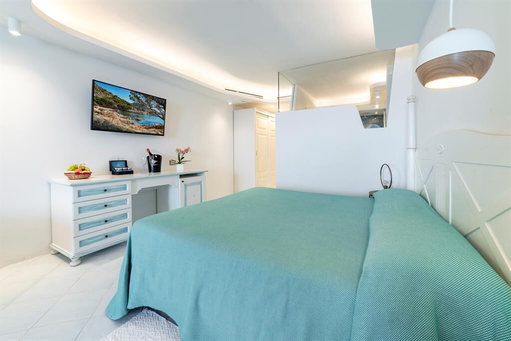 A modern bedroom with a bed, a desk, and a large window.