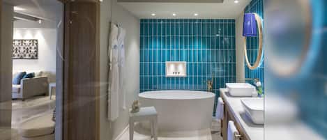 A modern bathroom with a freestanding bathtub, a vanity with two sinks, and a blue-tiled wall.