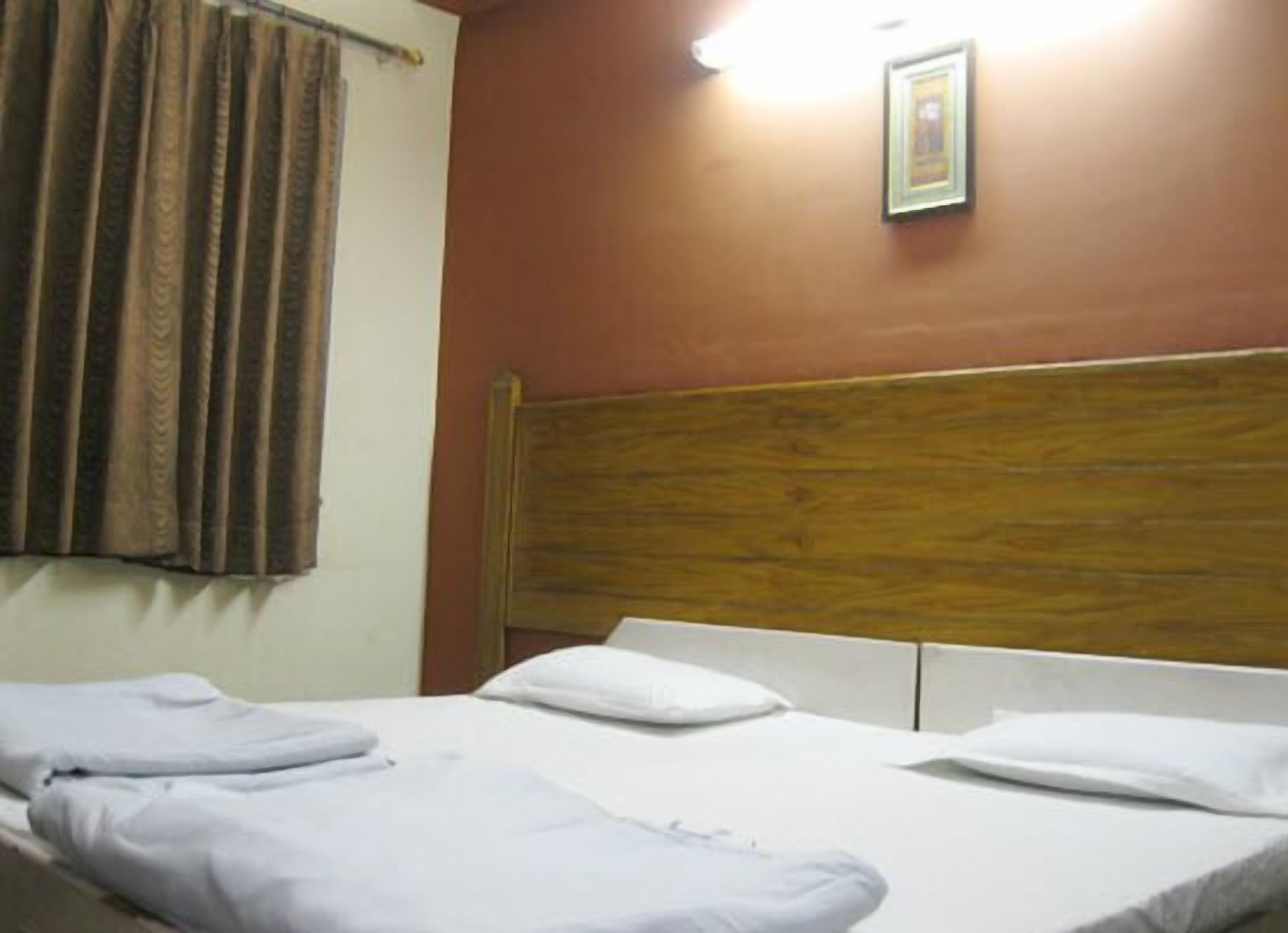 A hotel room with two beds, a wooden headboard, and a framed picture on the wall.