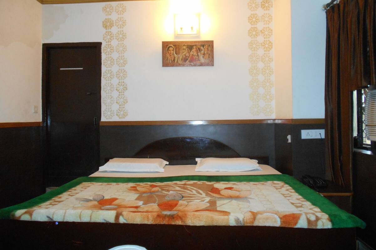 Ein Hotelzimmer mit Bett, Nachttisch, Wandlampe und Tür.