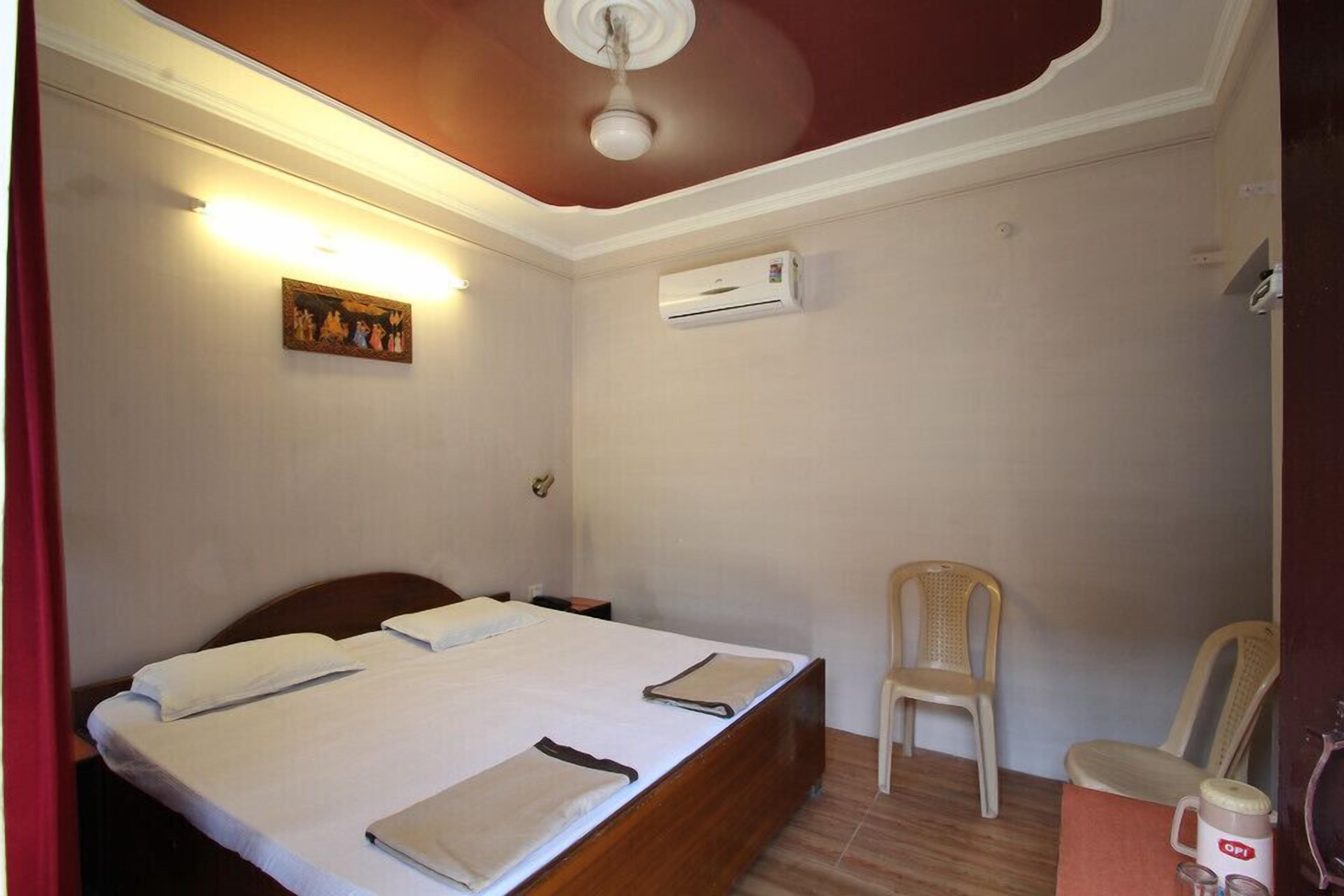 Una camera da letto con un letto, una sedia, un condizionatore d'aria e un quadro appeso al muro.