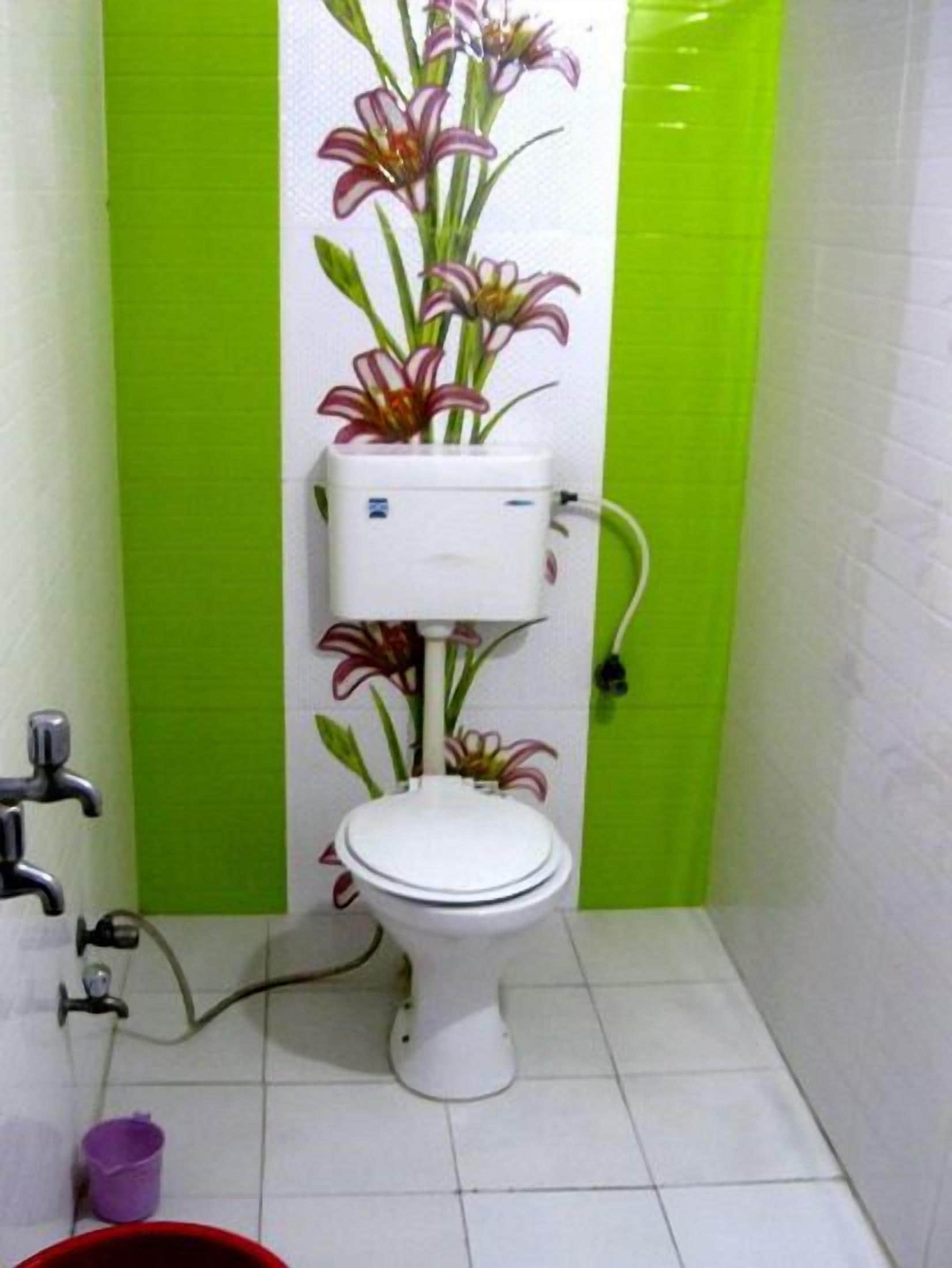A bathroom with a white toilet, green walls, and a floral decal on the wall.