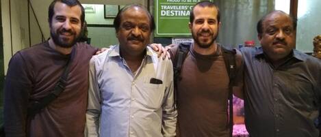 A group of four men standing in front of a sign that reads "2016 TRAVELERS' CHOICE" and "TRIP ADVISOR."