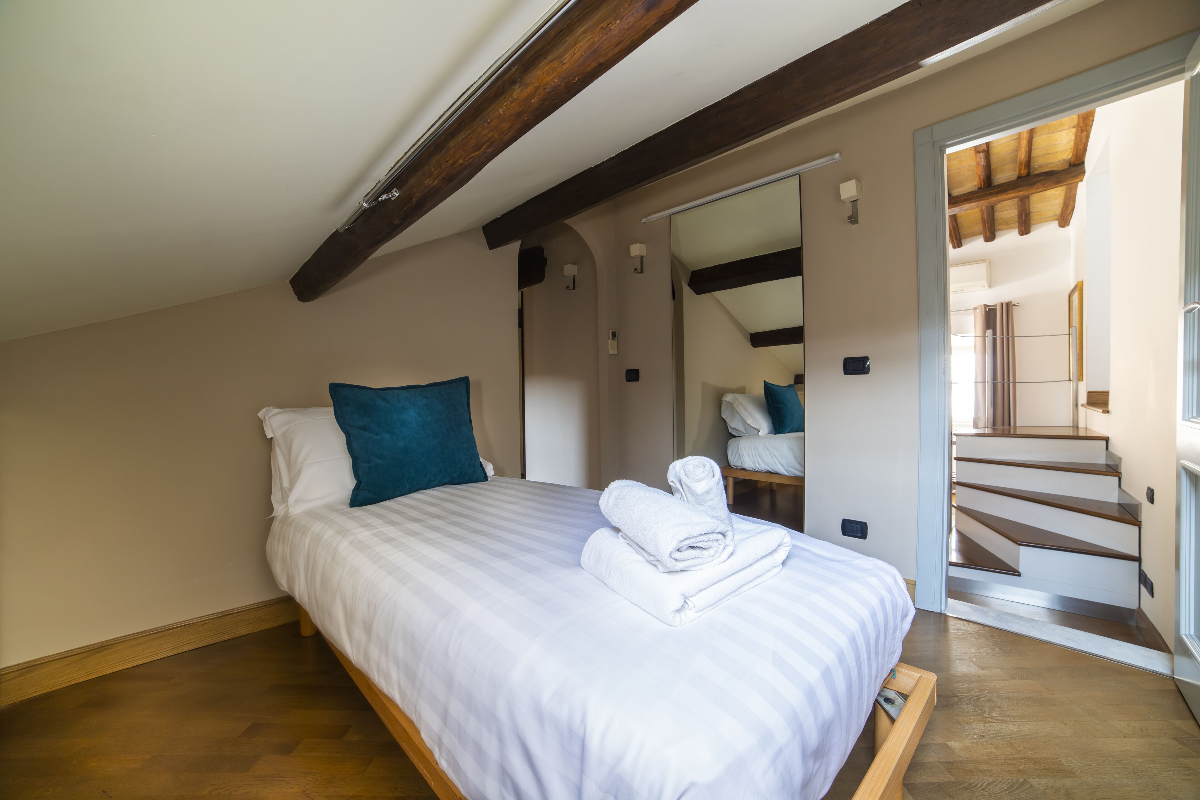 Une chambre à coucher avec un lit, un oreiller bleu et une serviette blanche soigneusement pliée.
