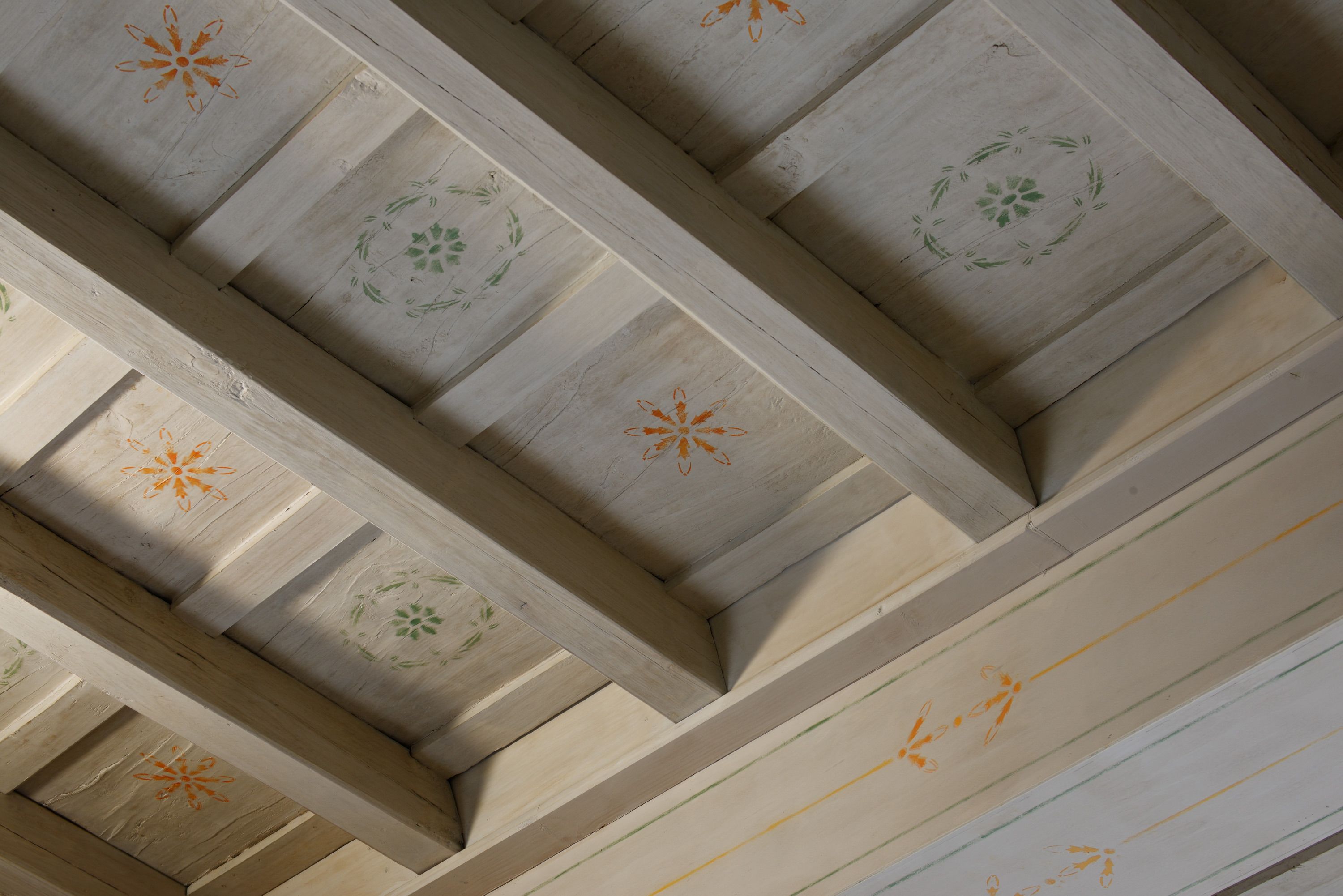 A ceiling with wooden beams and floral patterns.