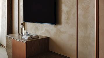 Een moderne badkamer met een houten wastafelmeubel, een spiegel, een flatscreen televisie en een handdoekhouder.