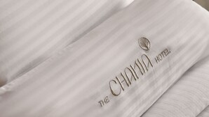 A hotel pillow with a logo and text indicating 'The CHAMIA HOTEL.'