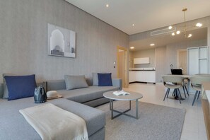 Een moderne woonkamer met een grijze bank, een salontafel, en een eethoek met stoelen en een tafel.