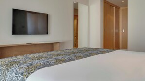 Ein modernes Hotelzimmer mit einem großen Bett, einem flachbildfernseher an der Wand und einem Holzschrank.