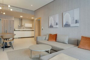 A modern living room with a sofa, coffee table, and a dining area with a chair and table. - Pestana Casablanca (Casablanca)