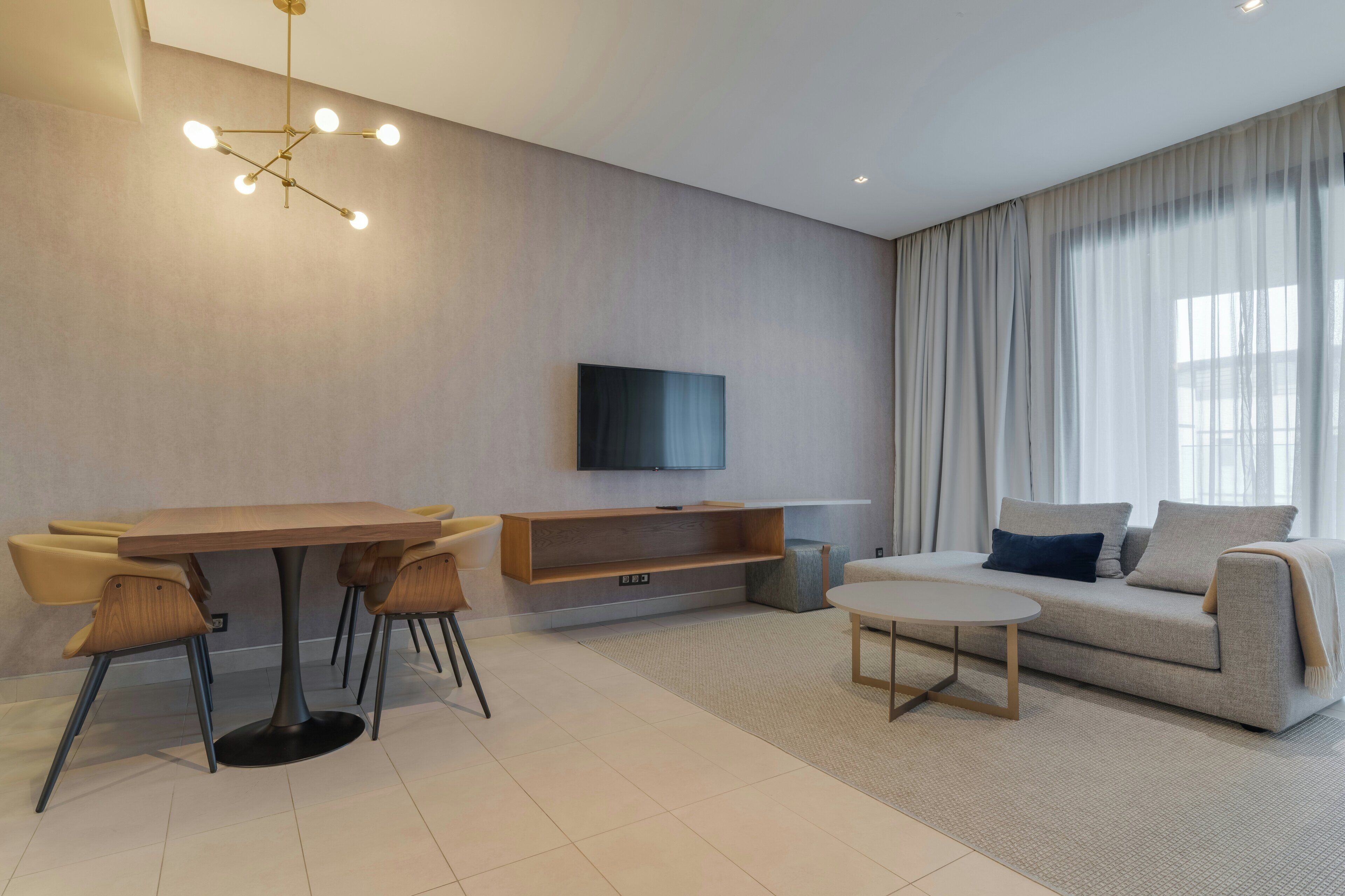 A modern living room with a dining table, sofa, and TV.