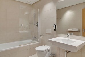 Een moderne badkamer met een douche met glazen wand, een wit wastafelmeubel en een toilet.
