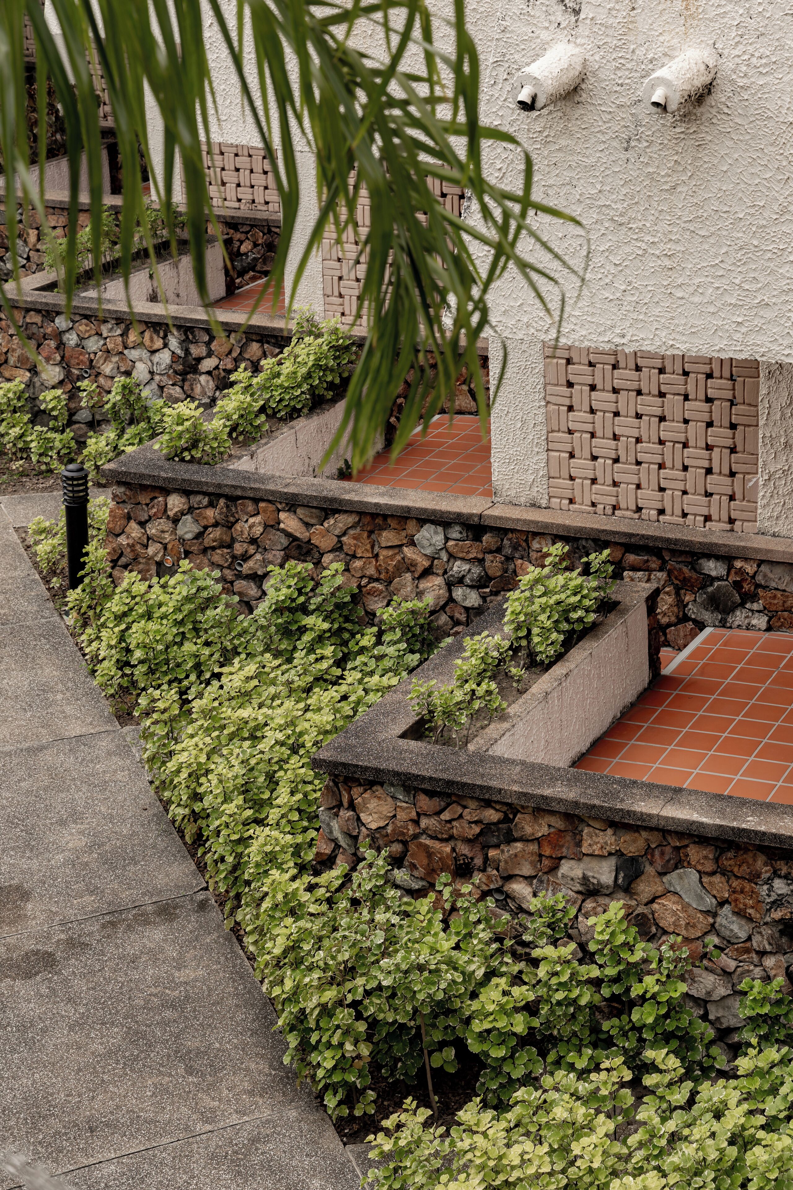 A landscaped garden area with stone walls, a brick pathway, and green foliage.