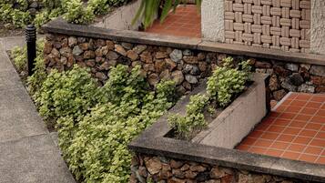 A landscaped garden area with stone walls, a brick pathway, and green foliage.