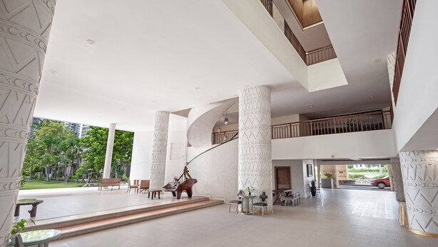A spacious lobby with high ceilings, large columns, and a central staircase. There are seating areas and a view of the outdoors. - Hotel Tropicana Pattaya (Pattaya)
