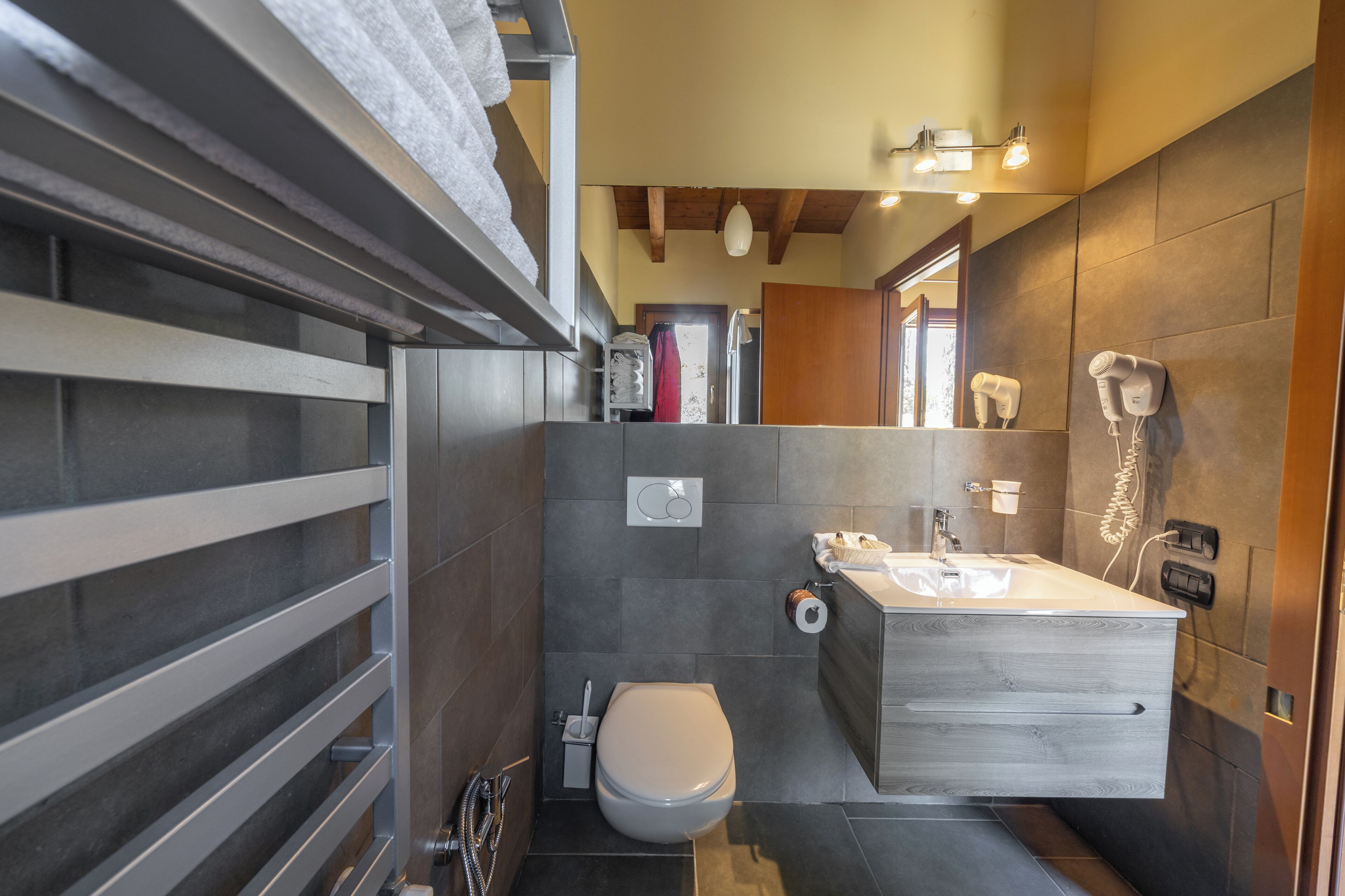 Un baño moderno con un espejo grande, un lavamanos y un inodoro.