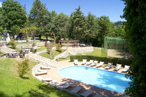 A swimming pool surrounded by lounge chairs, a small building, and a fenced area with trees. - La Valle Dei Caprioli - B&B (Montescudo)
