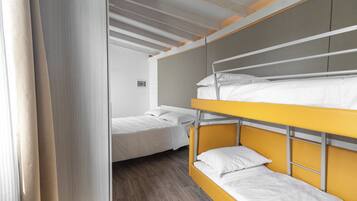 A bunk bed room with a wooden floor and white bedding.