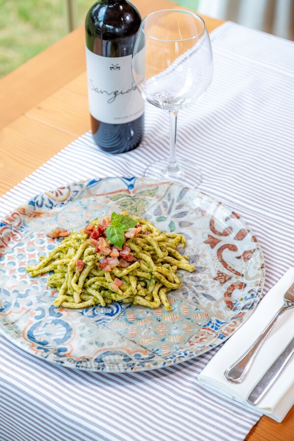 Une assiette de pâtes, une bouteille de vin et un verre sur une table.