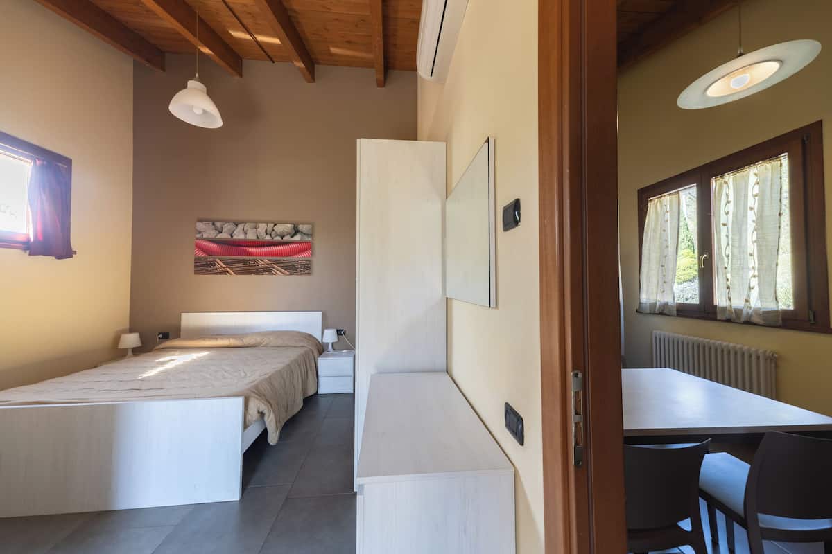 A bedroom with a bed, bedside tables, a desk, and chairs.