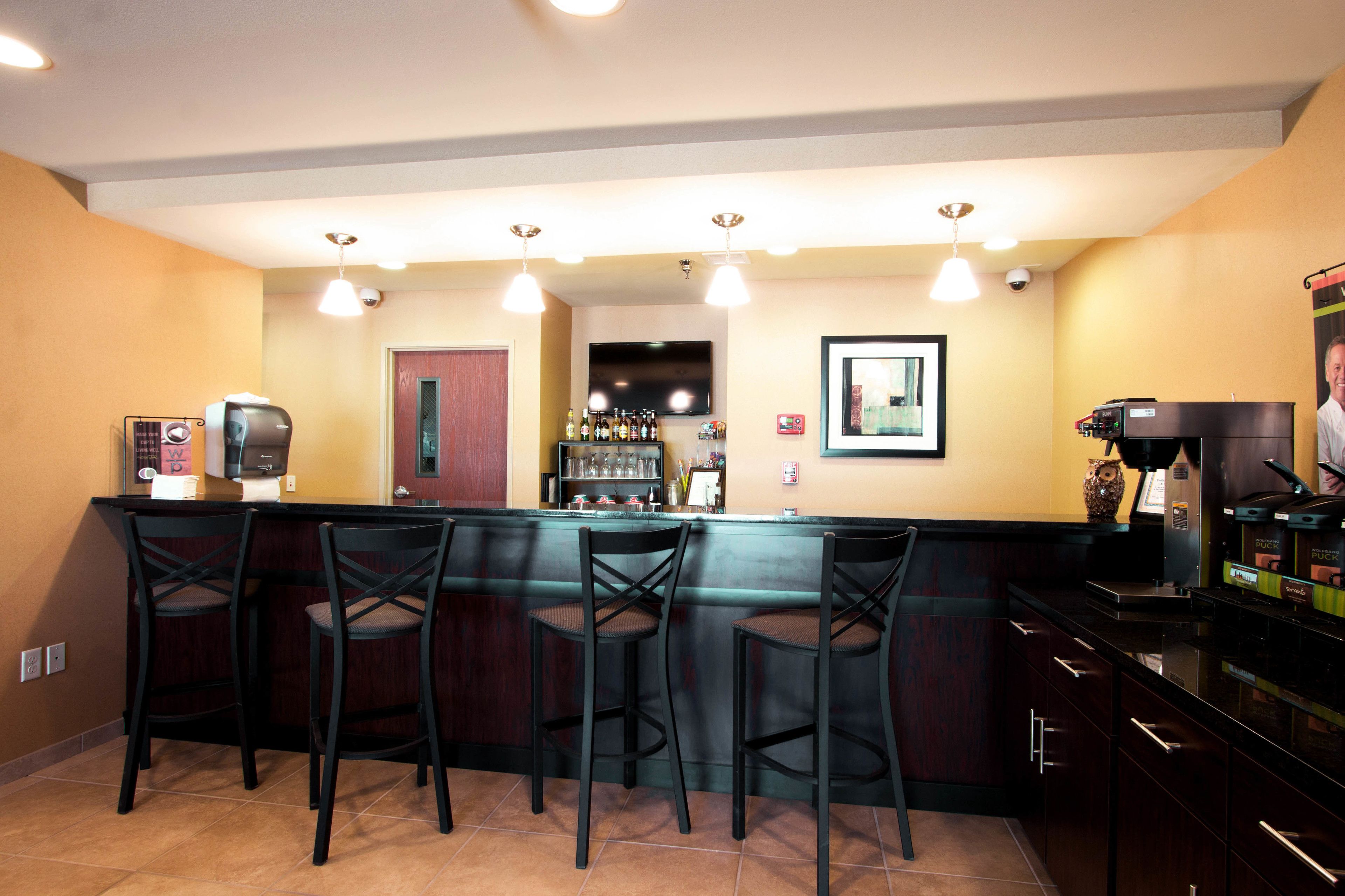 A bar area with a counter, bar stools, and a television mounted on the wall.