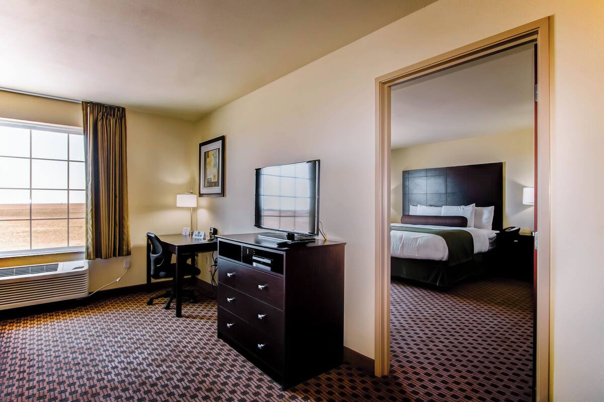 A hotel room with a desk, chair, and a bed.