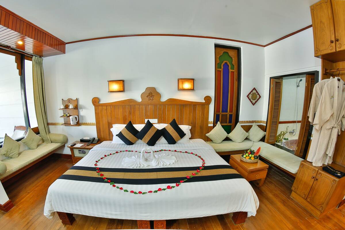 A well-appointed hotel room with a large bed, a sofa, a small table with a fruit bowl, and a wardrobe.