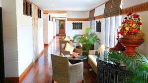 A hallway with wicker furniture, a large potted plant, and a wicker basket with flowers.