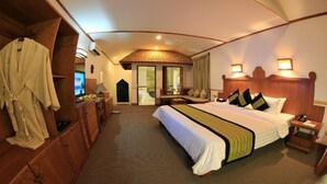 A hotel room with a large bed, wooden furniture, a desk with a computer, and a bathroom visible through an open door.