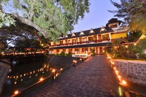 A traditional-style hotel with a wooden deck overlooking a calm body of water, surrounded by lush greenery. - Hotel Amazing Nyaung Shwe (Nyaungshwe)
