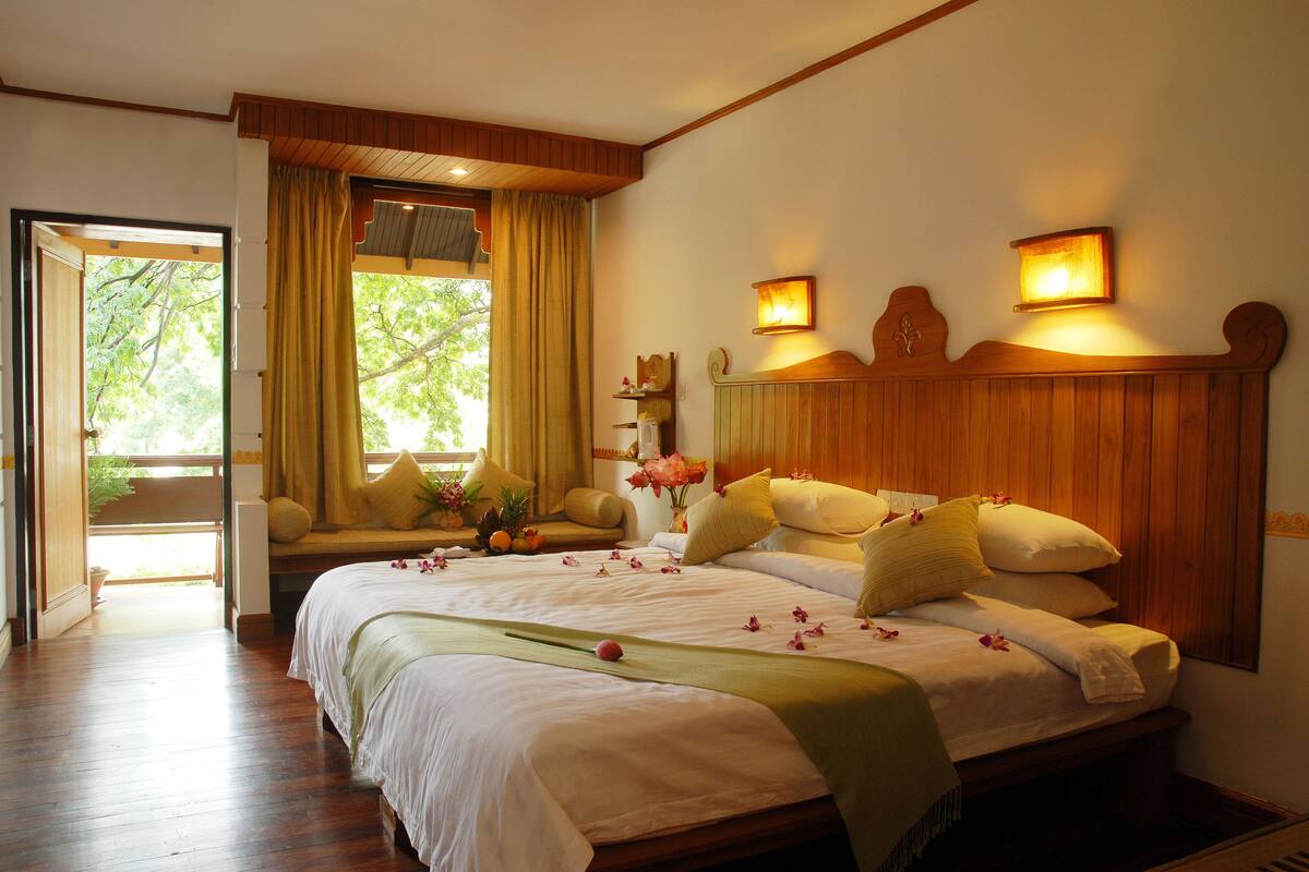 A spacious bedroom with a large bed, wooden headboard, and a view of the outdoors.