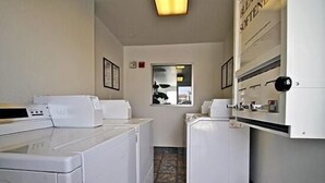 A laundry room with a washing machine, dryer, and a small window. - Hilltop Inn & Suites (Victorville)