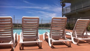 A poolside area with white lounge chairs and a clear blue sky. - Hilltop Inn & Suites (Victorville)